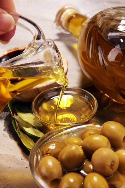 Botella de aceite de oliva virgen y aceite en un bol con algunas aceitunas
. - Foto, imagen