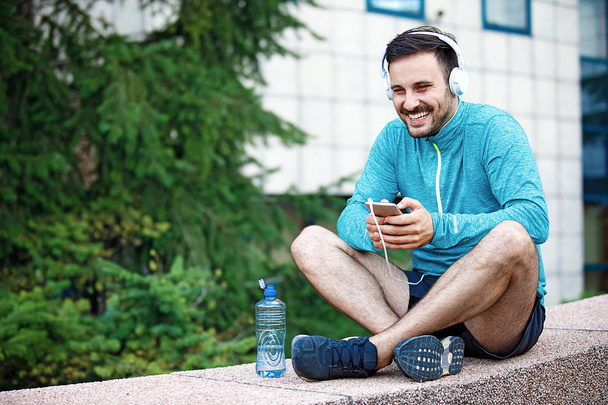 Man is listening music and relaxing after jogging. - Foto, Imagen