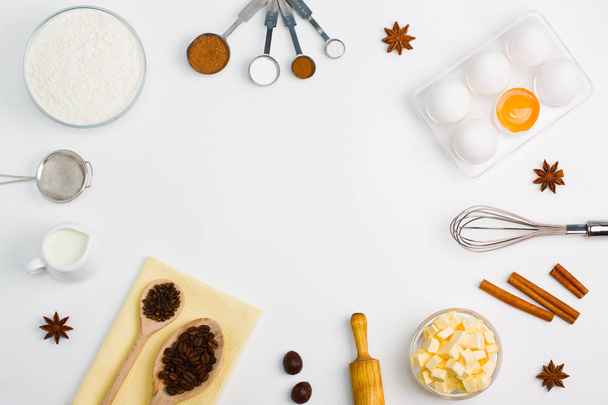 Cooking baking flat lay background with eggs, yolk, a cup of butter, a cup of flour, milk, spices - Photo, Image