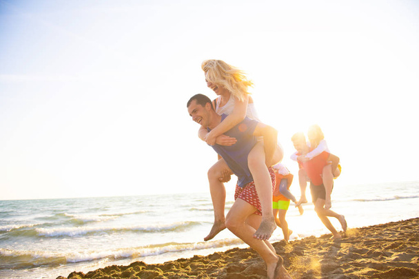 Друзья веселятся на пляже под закатом солнца
 - Фото, изображение