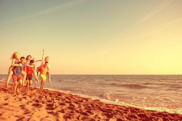 Amusement des amis sur la plage sous la lumière du soleil couchant
 - Photo, image