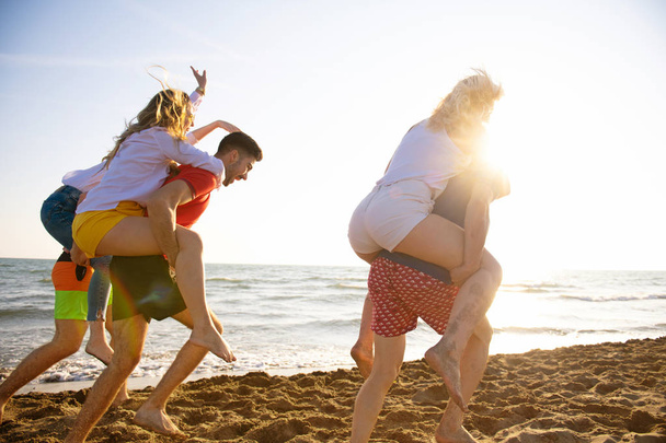 Amusement des amis sur la plage sous la lumière du soleil couchant
 - Photo, image