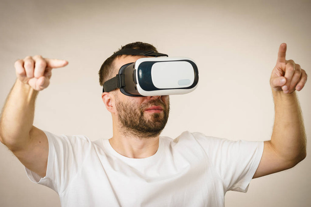 Adult short bearded guy exploring virtual reality wearing VR goggles being into technology. - 写真・画像