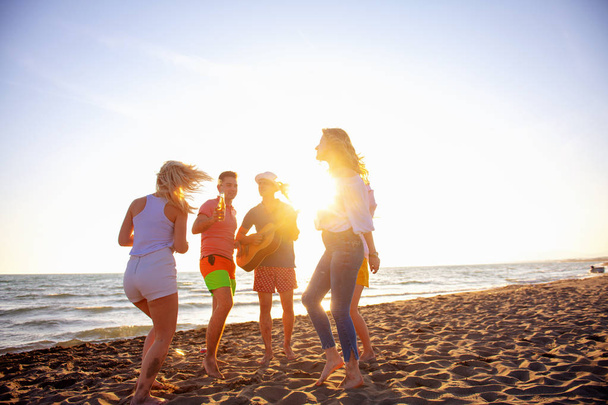 grupo de jóvenes felices bailando en la playa en el hermoso atardecer de verano
 - Foto, Imagen