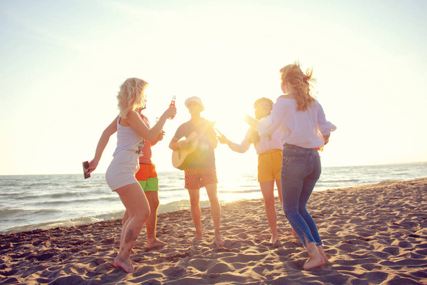 幸せな若い人たちの美しい夏の日没浜のダンスのグループ - 写真・画像