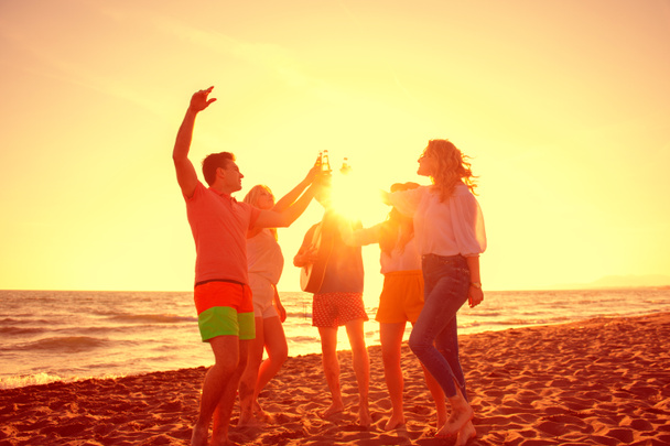 ryhmä onnellisia nuoria tanssimassa rannalla kauniina kesänä auringonlasku
 - Valokuva, kuva