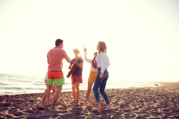 groupe de jeunes gens heureux dansant à la plage sur le beau coucher de soleil d'été
 - Photo, image