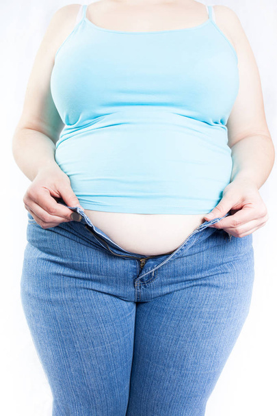 dicke Frau, die versucht, Jeans zu tragen (Übergewicht, Fettleibigkeit). isoliert auf weißem Hintergrund - Foto, Bild