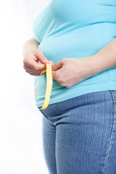 mujer gorda midiendo su estómago (sobrepeso, obesidad). Aislado sobre fondo blanco
. - Foto, Imagen
