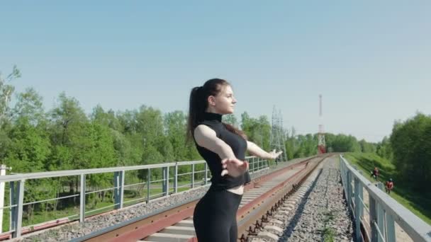 junge Brünette macht Atemübungen auf der Eisenbahnbrücke über die Autobahn - Filmmaterial, Video