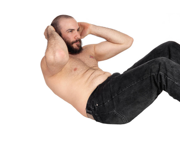 стройный красивый мужчина без рубашки и в джинсах, делающий желудок
 - Фото, изображение