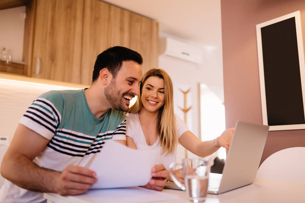 Feliz joven pareja calculando facturas en casa
 - Foto, imagen