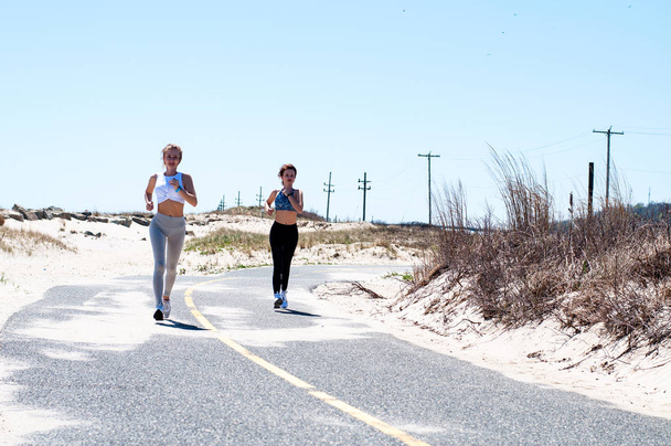 Fitness women running on beach. Happy girls woman jogging outdoors - Valokuva, kuva