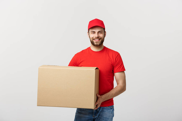 Nuori hymyilevä logistinen toimittaja punaisessa univormussa pitäen laatikkoa valkoisella taustalla
 - Valokuva, kuva