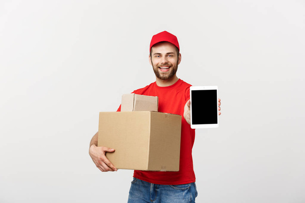 Online shopping, delivery, technology and lifestyle concept - smiling delivery man presenting tablet and holding boxes in his hand. Isolated over white studio background. - Fotoğraf, Görsel
