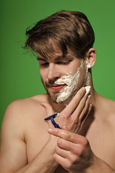 Man shave beard hair with razor on green background - Foto, Imagen
