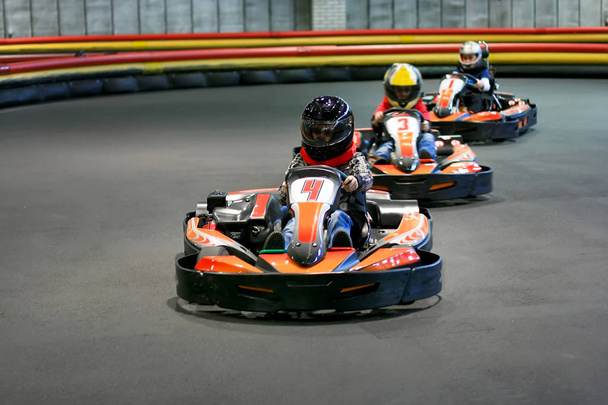Brovary. Ukraine. 14.03.2010 children in a helmets are in the go-karts on the karting track indoors - Foto, afbeelding