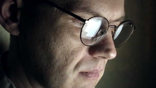 A man in glasses works late at night. He looks worried, he sees on the computer screen in front of him, a close-up - Imágenes, Vídeo