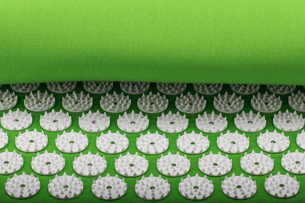Green fabric acupuncture massage mat with white plastic spikes - Photo, Image