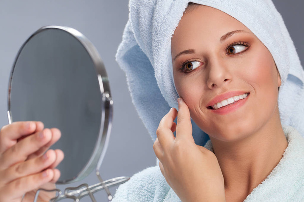 Beautiful spa woman holding mirror and touch her face - Fotoğraf, Görsel