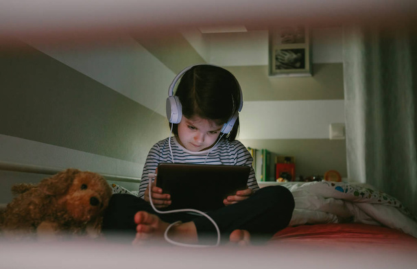Το κορίτσι με τα ακουστικά που βλέπουν το δισκίο - Φωτογραφία, εικόνα