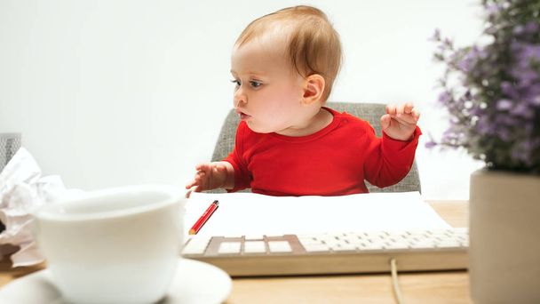 白い背景に分離されたコンピューターのキーボードに座って幸せな子供赤ちゃん女の子幼児 - 写真・画像
