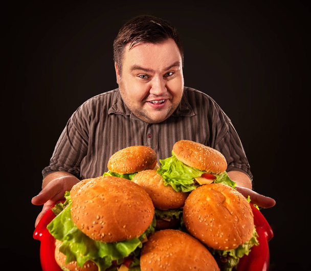 Un ciccione che mangia hamberger da fast food. Colazione per persona in sovrappeso
. - Foto, immagini
