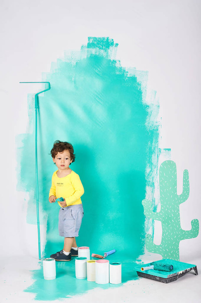 Cute little boy doing repairs in the apartment fun paints the wall  - Fotó, kép