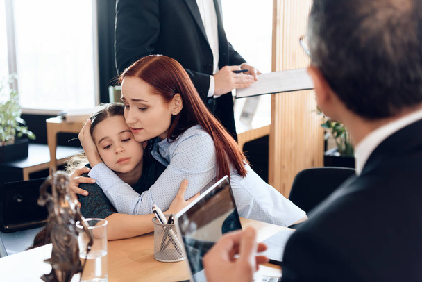 Young sad mother hugging little upset daughter sitting in lawyer office for divorce - Photo, Image