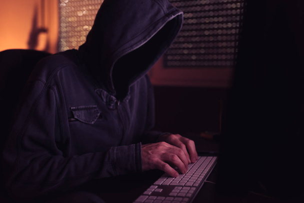 Computer hacker typing keyboard in dark interior, low key with selective focus - Φωτογραφία, εικόνα