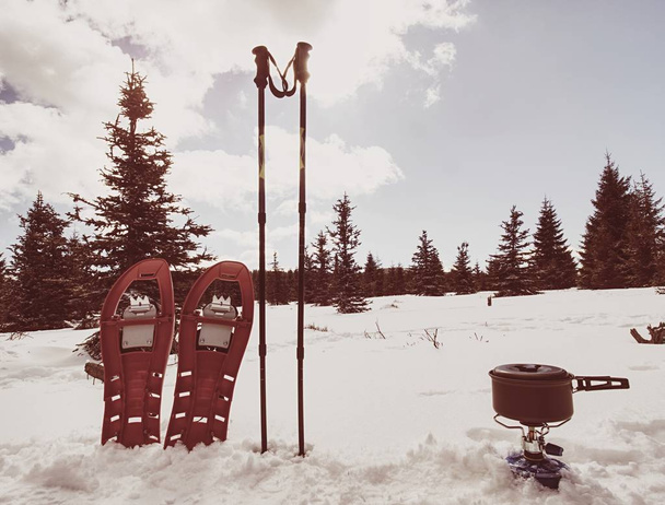 Cooking in front of tent in snow.  Hiker camping in winter mountains.  Man cooking food with portable gas cooker and light dishes. Burning gas stove and in kettle boiling water.  Snowy landscape - 写真・画像