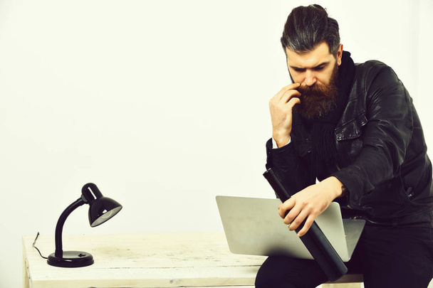 Bearded brutal caucasian hipster sitting on table with laptop - Foto, Bild