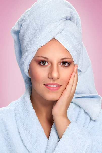 Beautiful spa woman in white bathrobe and towel touching her face - Foto, Imagem