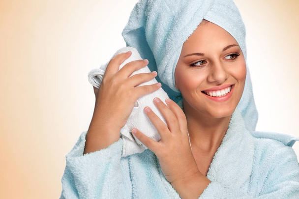 Beautiful spa woman in bathrobe smiling and holding towel - 写真・画像