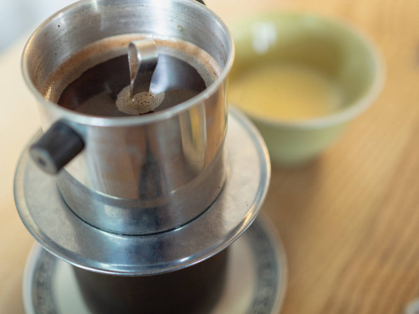 Традиционный вьетнамский капельный кофе с сгущенным молоком на деревянном столе утром
 - Фото, изображение