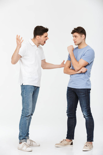 Retrato completo de dos jóvenes enojados discutiendo aislados sobre fondo blanco
 - Foto, imagen