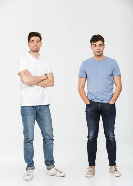 Full length portrait of two confused young men looking at camera isolated over white background - Foto, immagini