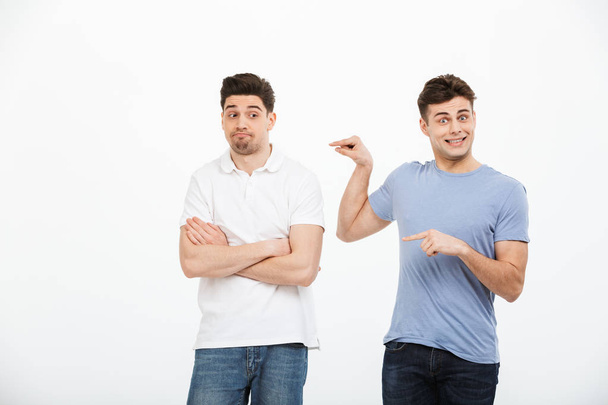 Portrait of two frustrated young men pointing fingers isolated over white background - Foto, Bild