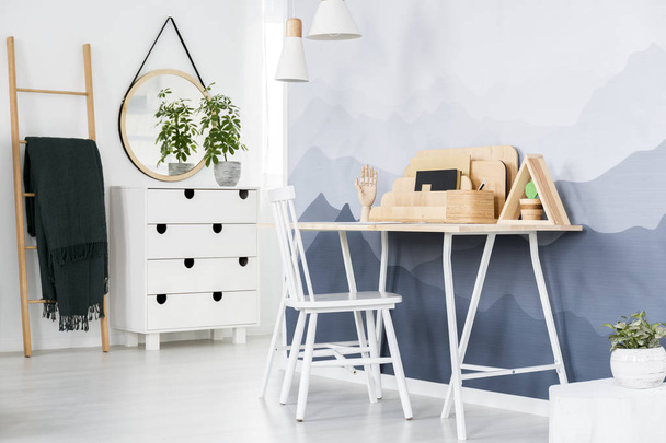 Silla blanca en un escritorio con organizador de madera de pie contra la pared con fondo de pantalla de montaña en el interior de la oficina casa brillante
 - Foto, Imagen