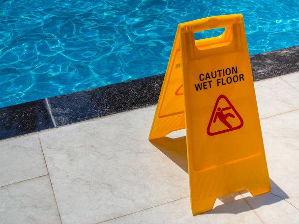 Yellow Caution Wet Floor Warning Plastic Sign Near Swimming Pool fot Safety - Photo, Image