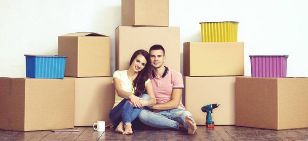 Young loving couple moving in a new house. Man and woman with tools and boxes. Home renovation and reconstruction concept. - Photo, Image