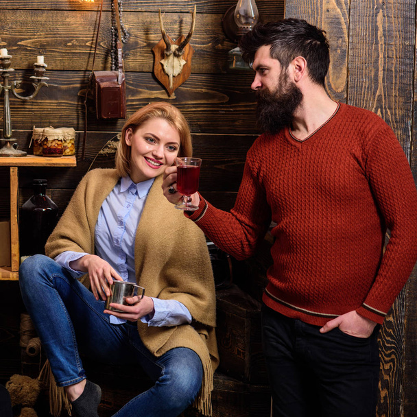Woman and man on smiling faces enjoy cozy atmosphere with hot drinks. Couple spend pleasant evening, interior background. Family, couple in love enjoy vacation in gamekeepers house. Coziness concept - Foto, immagini