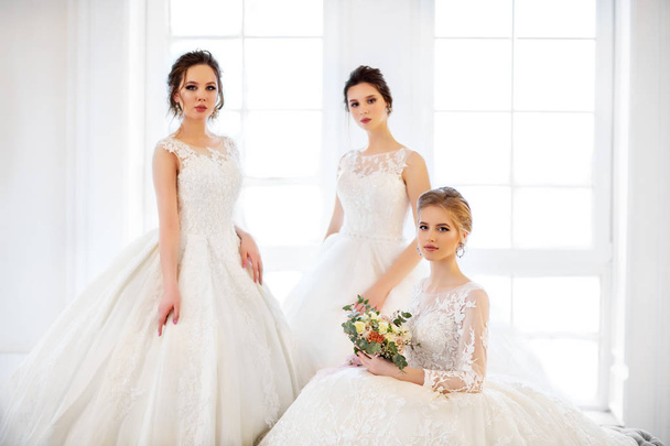 Tři mladé ženy s kytice na sobě svatební šaty - Fotografie, Obrázek