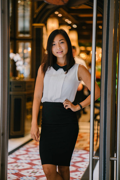 Professional portrait of a young, attractive, fit and cute Chinese Asian woman in an office or coworking space. She is smiling confidently - 写真・画像