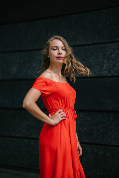 Portrait of a young, attractive Caucasian woman walking outdoor in park in the day. She was wearing a beautiful, light and comfortable orange dress and is smiling playfully. - Fotó, kép