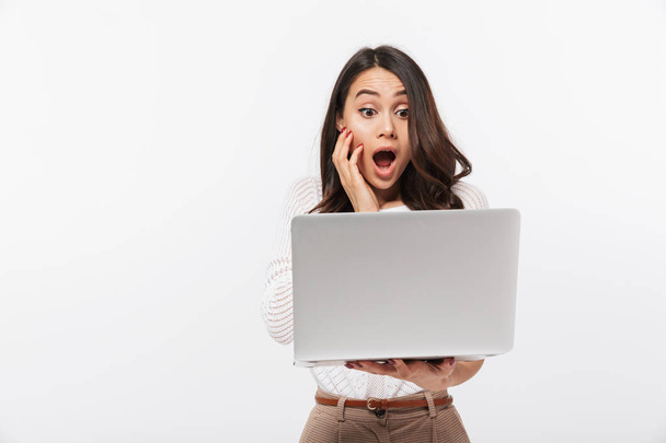 Portrait of a shocked asian businesswoman looking at laptop computer isolated over white background - Fotografie, Obrázek