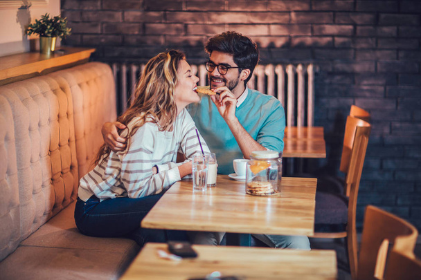 Young couple sitting in cafe drinking coffee and conversing - Photo, Image
