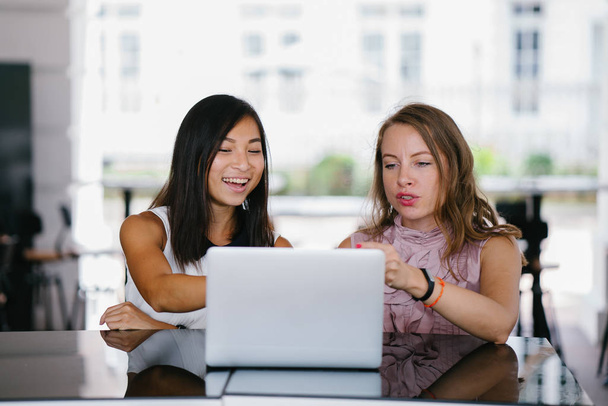 Portrait of a diverse team of two coworkers (a Chinese Asian woman and a Caucasian white woman) looking over a DCF cashflow model on a laptop computer in the day. - Фото, зображення