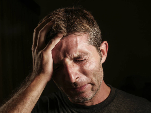 Close-up van portret van triest en depressief man met hand op gezicht op zoek wanhopige gevoel gefrustreerd en hulpeloos huilen ellendig in depressie en verdriet gelaatsuitdrukking geïsoleerd zwarte bg - Foto, afbeelding