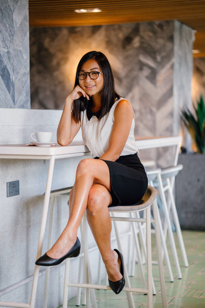 Business portrait for a young, attractive, athletic and cute Chinese Asian woman with coffee posing  in cafe - Photo, Image